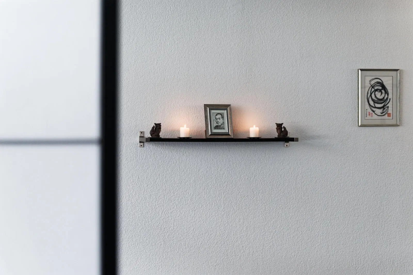 Ein Altar mit einem Bild, zwei Kerzen und zwei japanischen Shisa